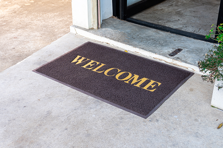 [IMAGE a dark brown mat with yellow letters spell out Welcome]