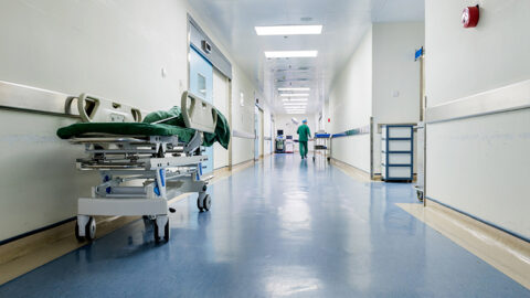 [IMAGE a hospital corridor with a bed and hospital personnel at the very end of the corridor]