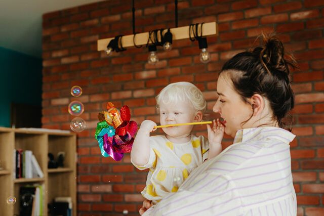 [IMAGE a mother holds a child who is sucking on a multicoloured toy]