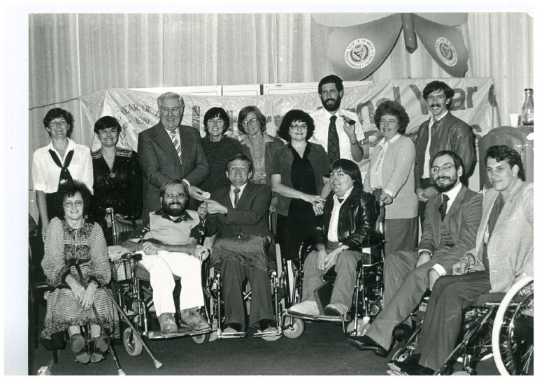 A black and white group photo of PWDA staff smiling.