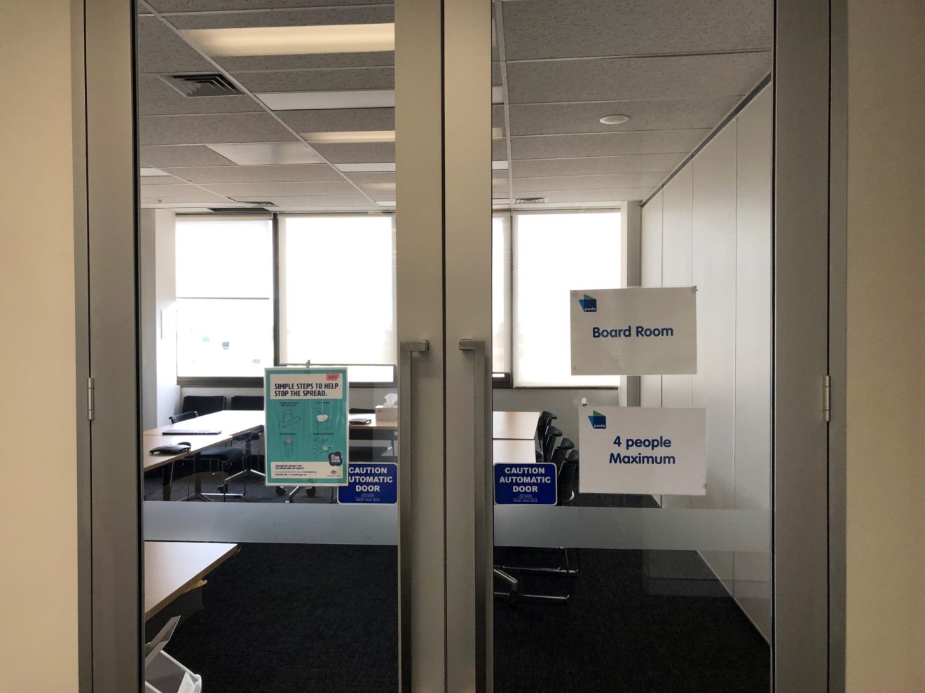 Photo of the automatic doors to enter into the boardroom. Signs say 'Caution: Automatic door'