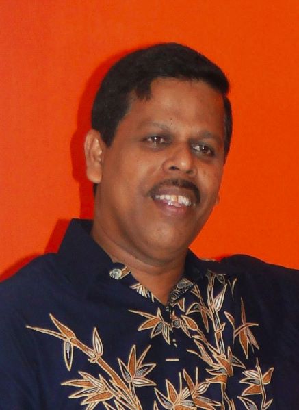Photo of Sunil Fernando looking off camera. He is wearing a shirt with leaves on it.