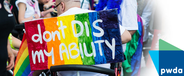 [IMAGE: Bright rainbow coloured sign has the words Don't DIS my ABILITY in white letters]
