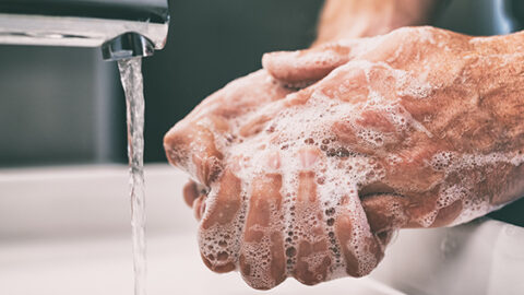 [IMAGE a person washes their hands with running water from a tap]