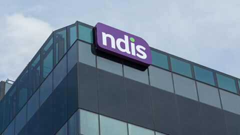 [Image: branded purple and white NDIS logo on building]
