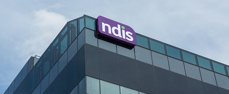 [Image: branded purple and white NDIS logo on building]