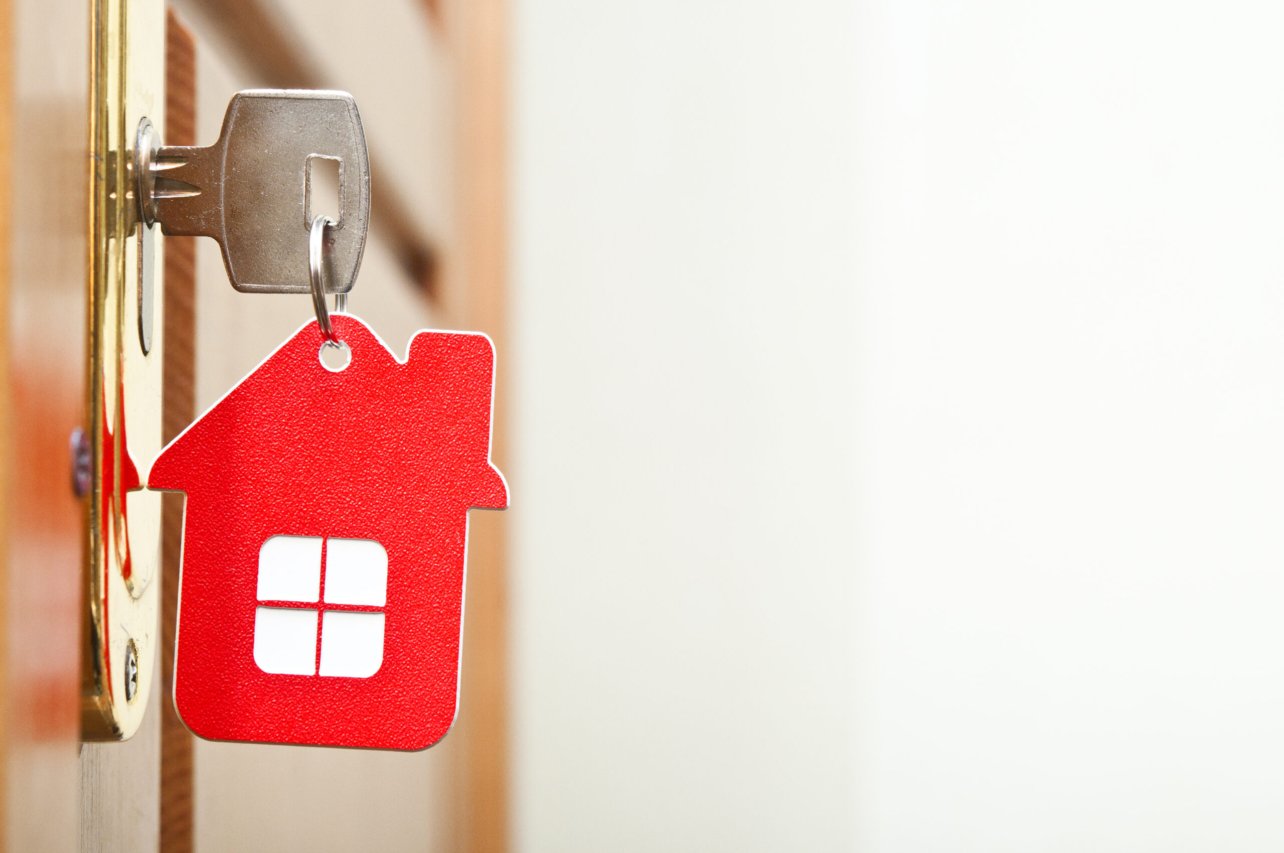 A key ring in the shape of a red house attached to a key in a door
