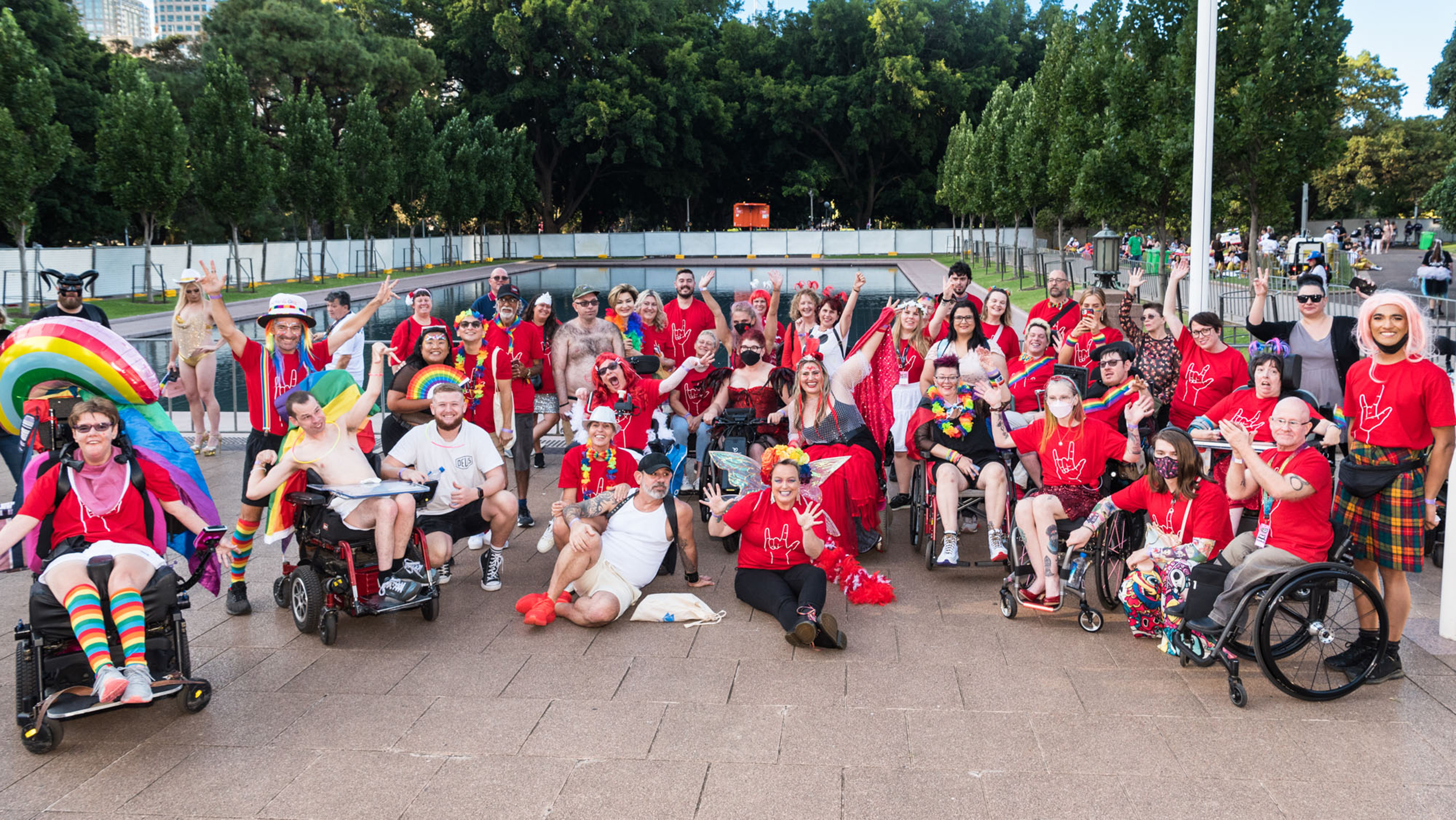 A group photo of people weariing red shirts and rainbow accessories.