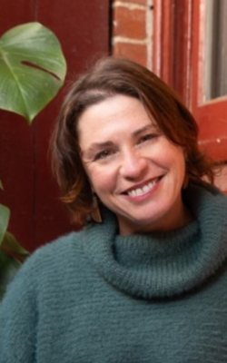 Headshot of Eva Sifis wearing a forest green turtleneck.