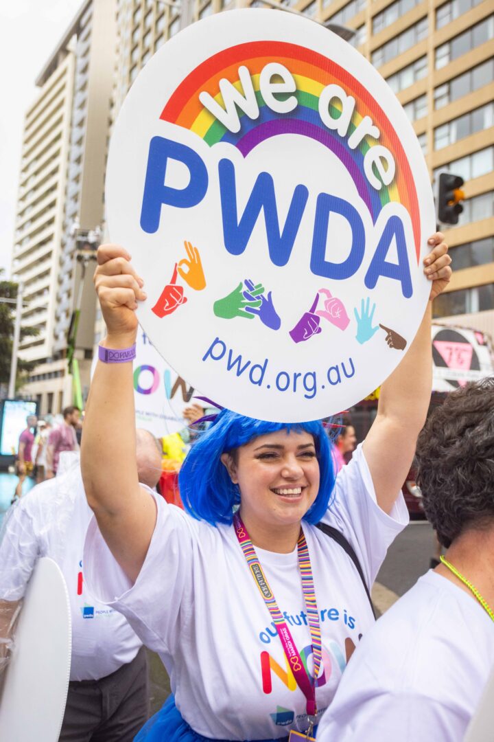 PWDA staff holding a We are PWDA sign at 2024 Mardi Gras parade