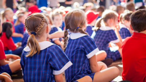 Children in school uniforms sitting at an assembly in an Australian school.