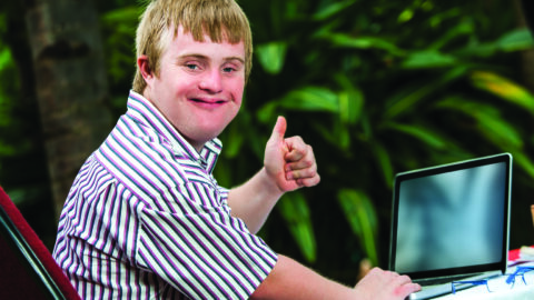 Man at computer smiling and giving a thumbs up sign