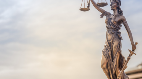 Statue of lady justice standing with scales held in the air and sword by her side