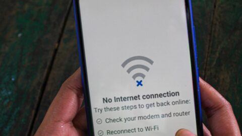 Hands holding a phone that shows the no internet icon and text says no internet connection