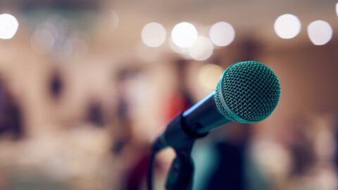 A microphone with a blurred background which contains lights and people