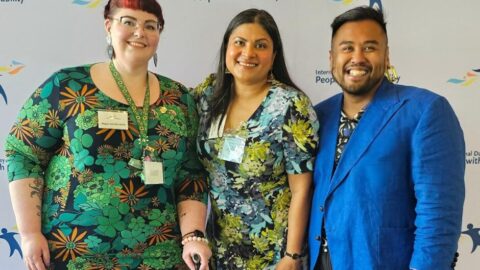 Deputy CEO Megan Spindler Smith, Sara Shams, a 2024 IDPWD Ambassador and MC from DSS morning tea and Senior Manager of Policy, Giancarlo De Vera standing in front of a background with IDPwD logos.