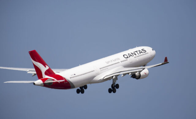 Image shows a Qantas airplane taking off into the sky. A white plane with red tail and Qantas logo