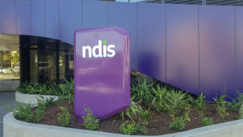 Large purple sign outside entrance to the NDIS headquarters.