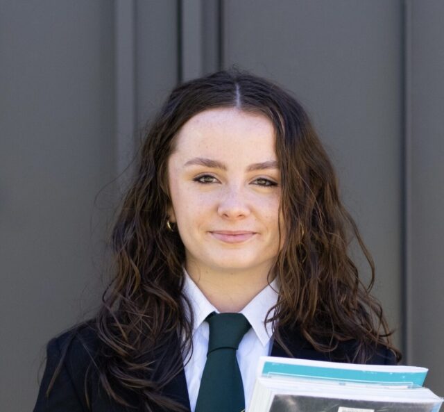 PWDA member Caitlin Blanch is holding a folder containing papers and wearing a jacket and tie