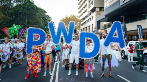 PWDA members and staff hold up PWDA letters in marshalling area at 2025 Mardi Gras