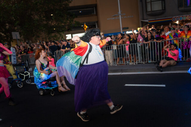 PWDA member walks up Oxford Street flaring a PWDA rainbow flag 