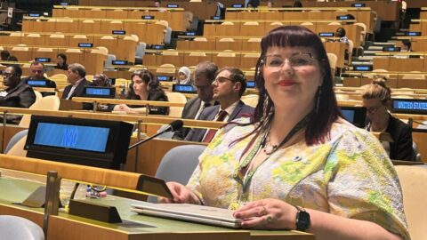 Megan Spindler Smith in a vibrant top speaking at the United Nations
