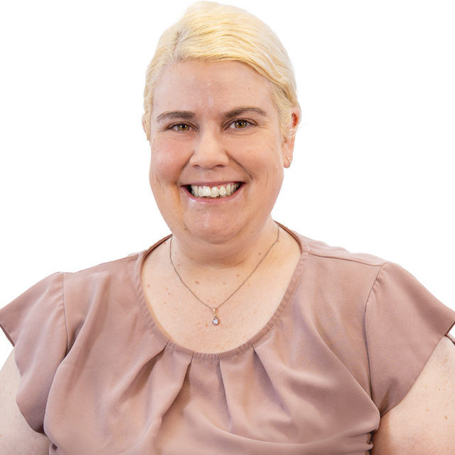 Smiling woman with short blonde hair wearing a pink blouse and a pendant necklace (portrait).